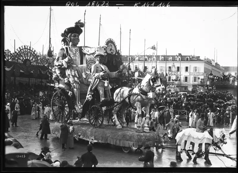 Photographie de 1912 : un char surmonté d'un grand roi de carnaval en carton-pâte avance devant la foule à Nice
