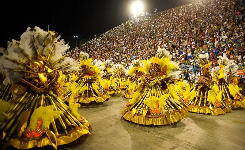 Un groupe de danseurs en costumes dorés à larges jupes tourne sur la piste devant des tribunes pleines