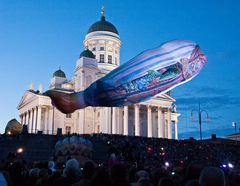 Une immense créature marine gonflable flotte de nuit devant la cathédrale blanche d'Helsinki, au-dessus d'une foule
