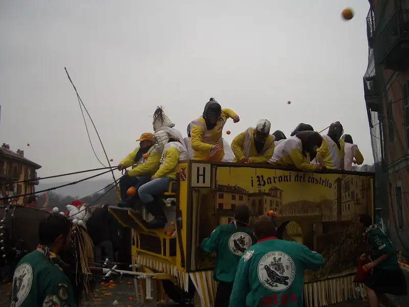 Lanceurs d'oranges casqués sur une charrette, face aux équipes à pied, des oranges volent dans l'air