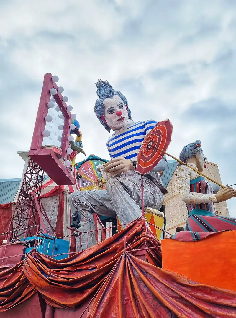 Char géant : un clown en marinière tenant un parapluie, devant une grande roue de fête foraine